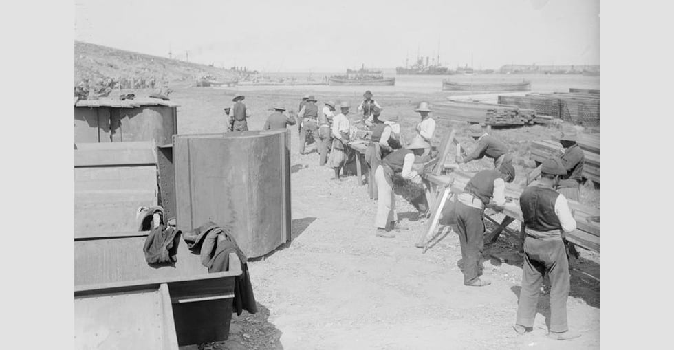 Civilian carpenters at work at Mudros. In the background the shipping in the harbour can be seen.