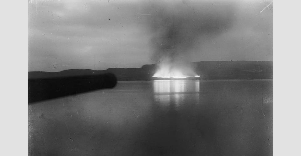 Distant view from the battleship HMS Cornwallis of stores burning on the beach after the evacuation of Suvla Bay, December 1915.
