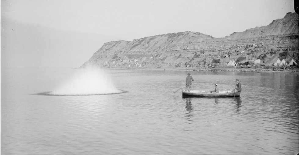 Officers in a small boat using grenades to stun fish off Cape Helles