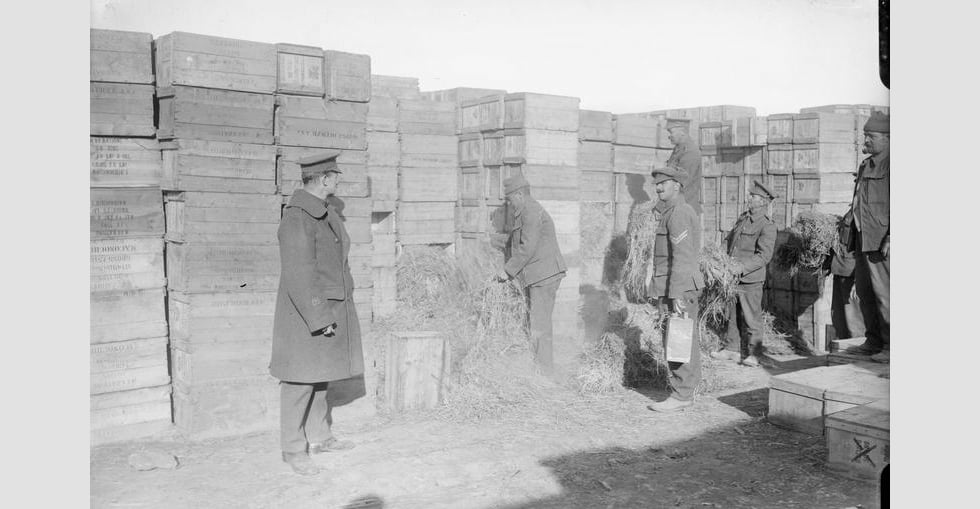 Hay and petrol being placed among the boxes of stores in a dump at 'A' West Beach, Suvla Point, to be burnt on evacuation, December 1915.