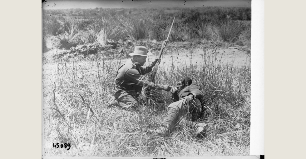 English soldier giving water to a wounded Turkish