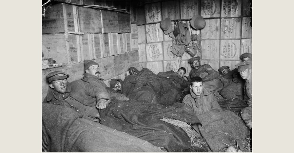 Frost-bitten soldiers lying on straw in shelters constructed of biscuit boxes at a store dump at Suvla, after the frost at the end of November 1915.
