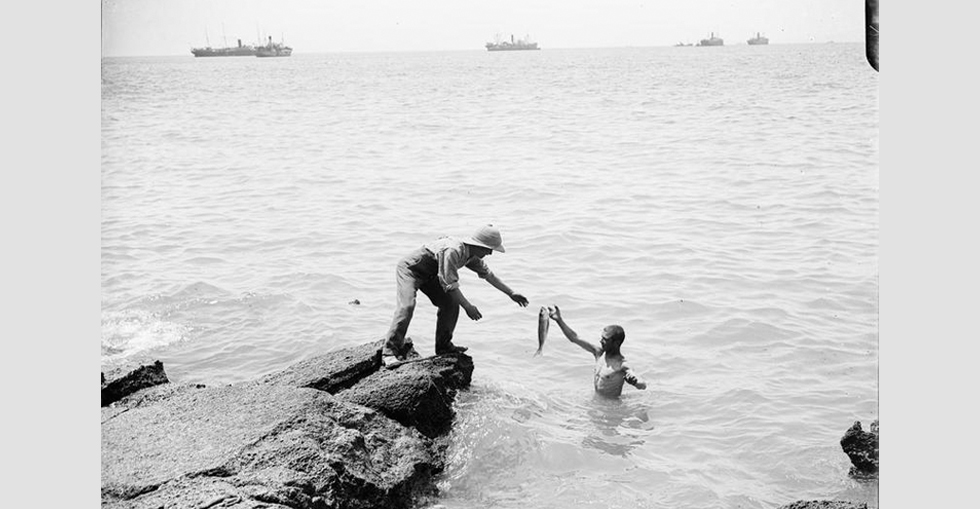 Soldiers collecting fish killed by a shell from an 'Asiatic Annie